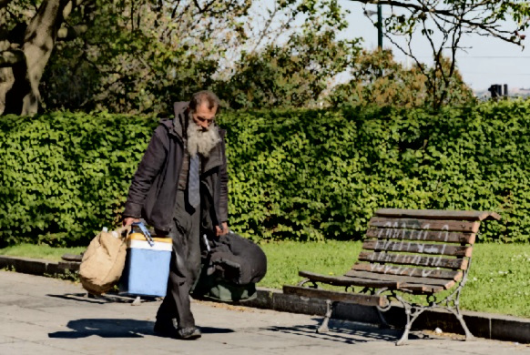 A homeless man walks in a park.
