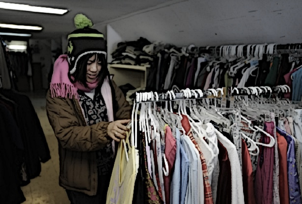 A woman searches a clothing rack at a homeless shelter.