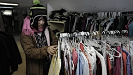 A woman searches a clothing rack at a homeless shelter.