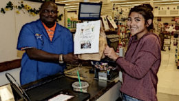 A woman shows her EBT groceries at a checkout counter.